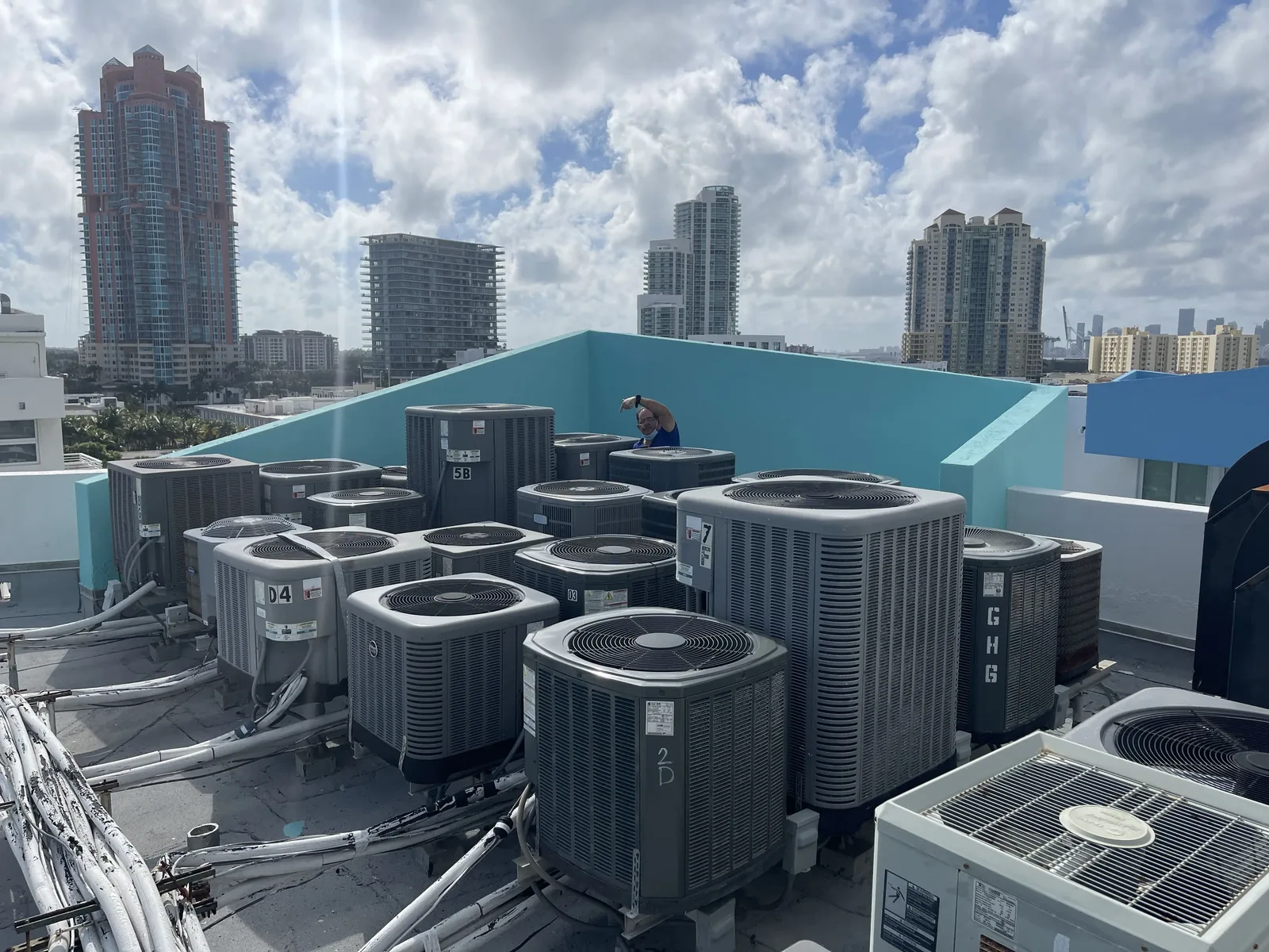 A Dade Super Cool technician working among rooftop condenser units on a Miami Beach apartment building